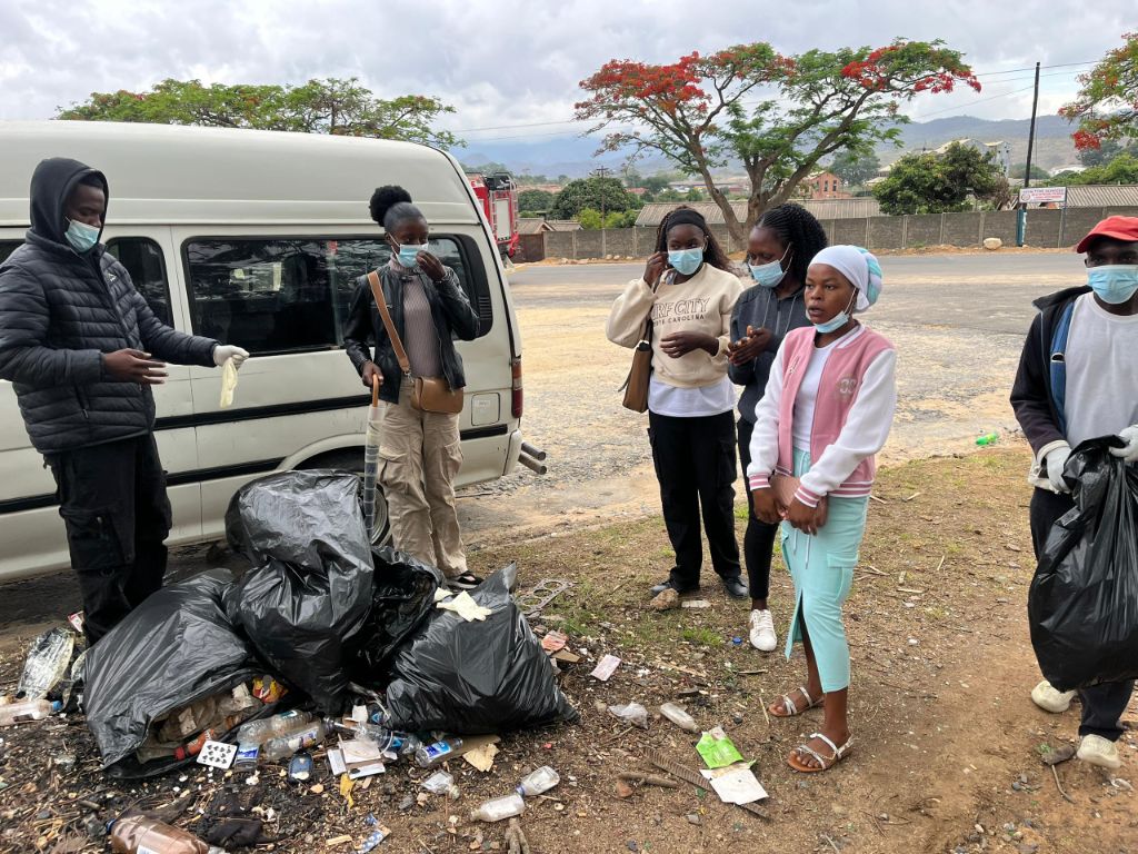 YES Zimbabwe volunteers standing with collected waste during a roadside clean-up campaign