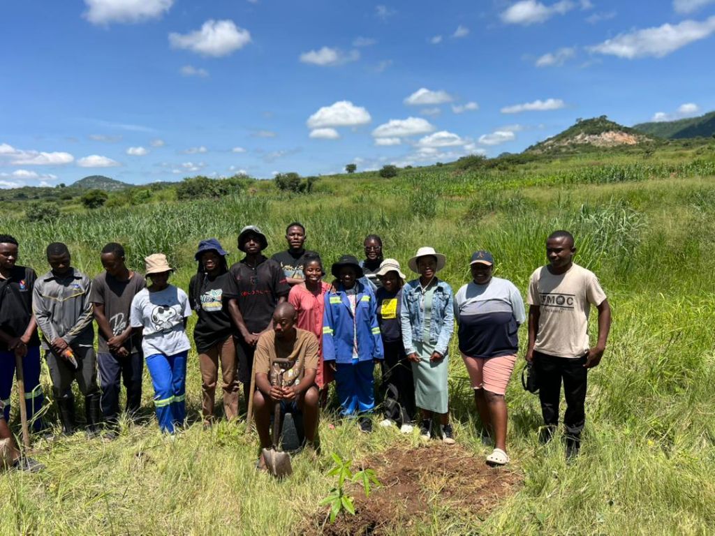 YES Zimbabwe members gathered during a community tree planting activity in a grassy landscape